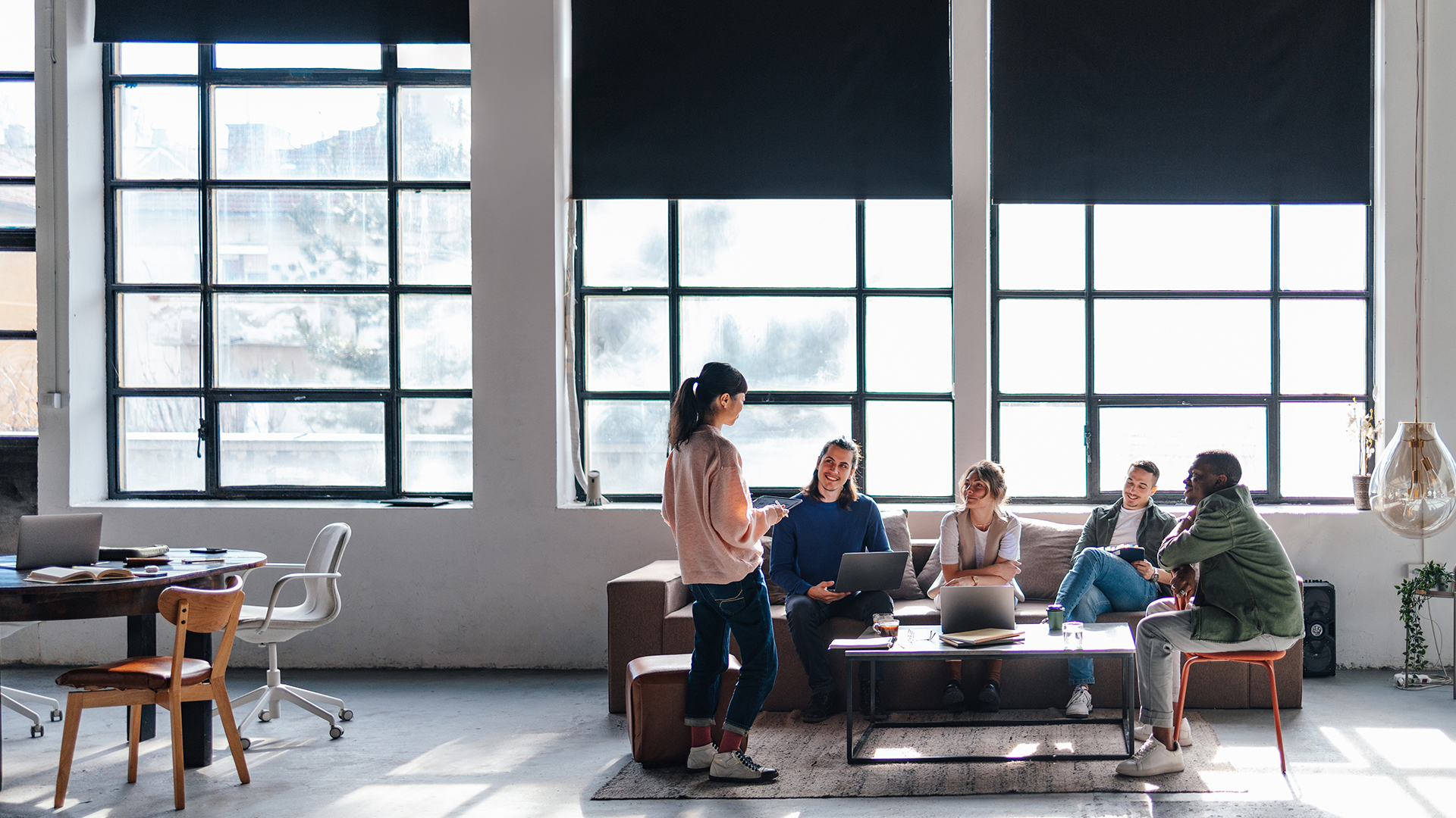 Employees in an open-concept office in front of a large window.