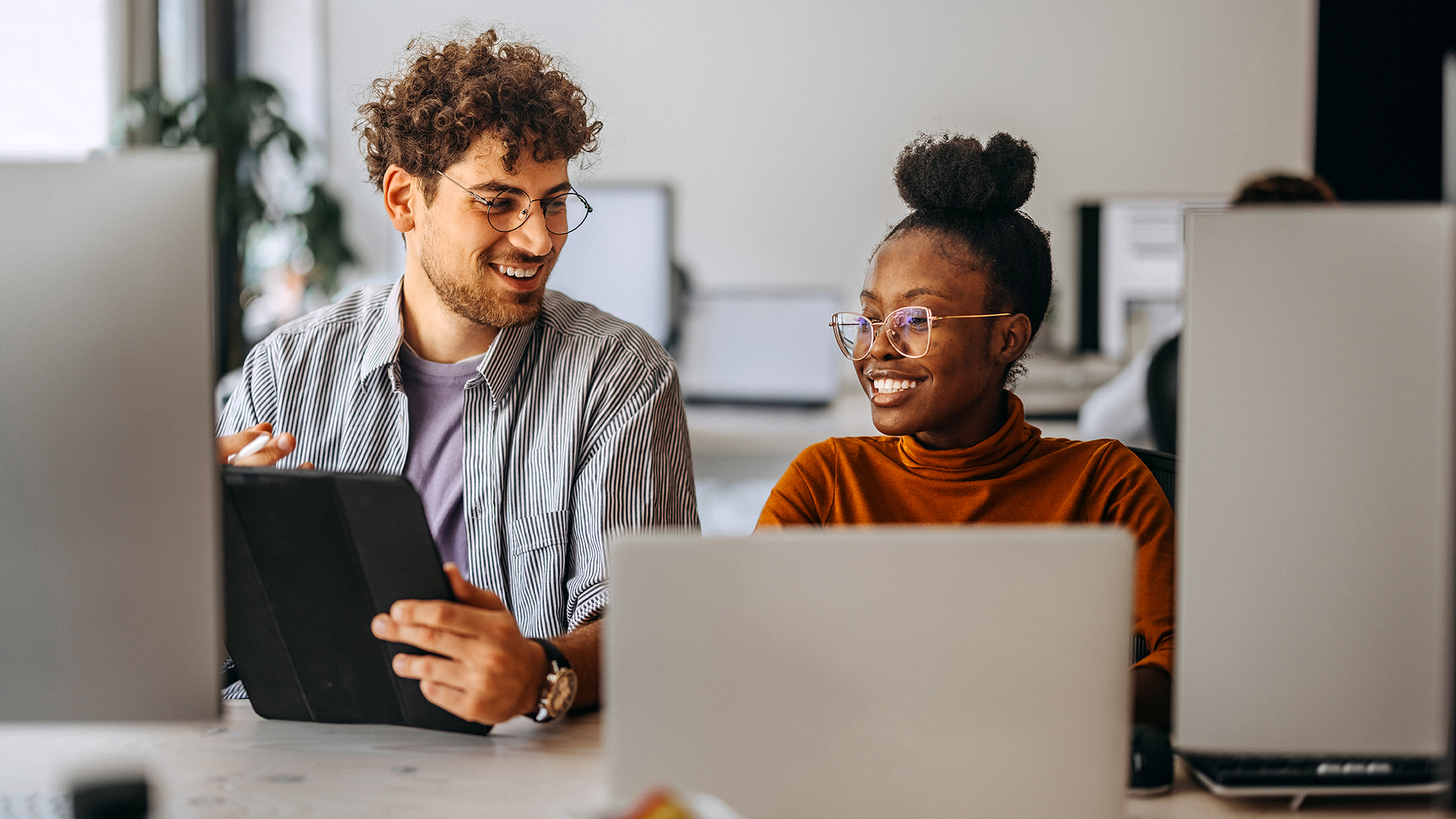 Two people sitting in front of a laptop and laughing.