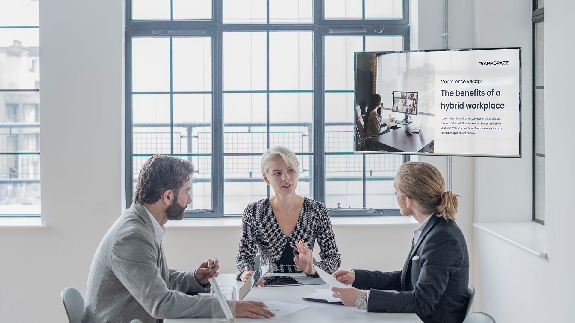 Three people sitting at a meeting table and talking.